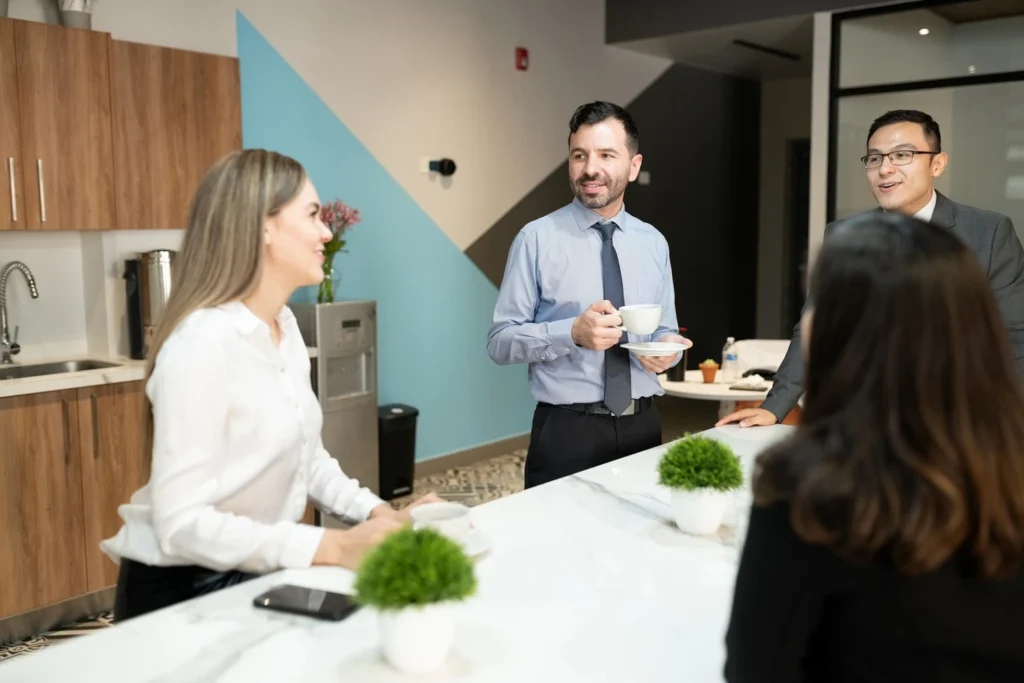 Law firm staff chatting over coffee in a modern office break room.